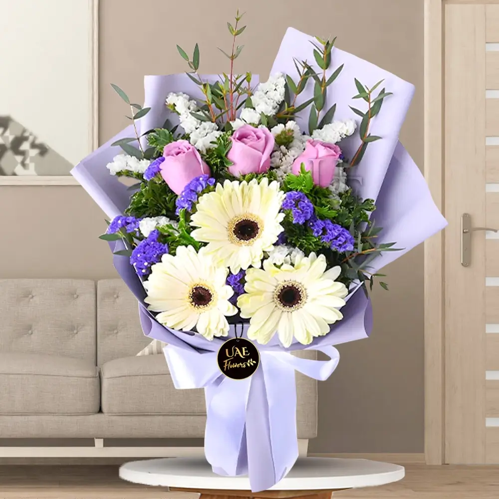 bouquet of 3 purple roses, white gerberas, statice, tea leaf and parvifolia