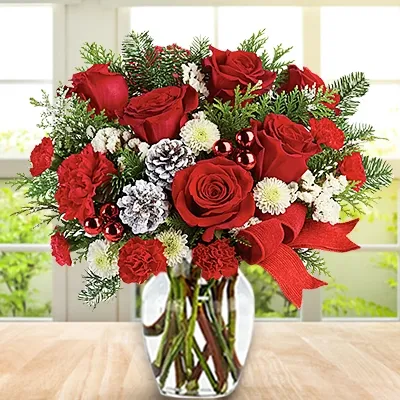 6 red roses, 4 red carnation, 3 white chrysanthemums & red christmas ornaments along with green fillers in a glass vase