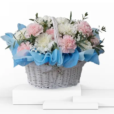 white & pink carnation flower basket with blue paper as decoration around it.