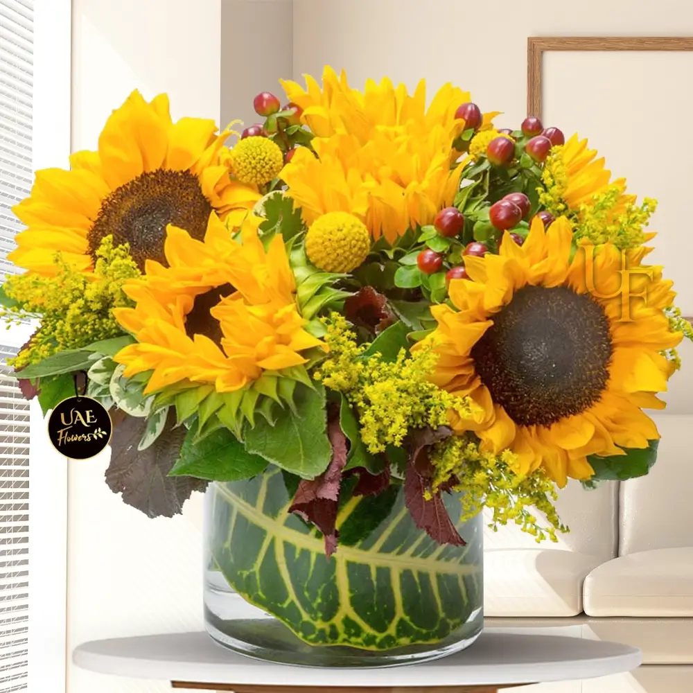 10 sunflowers, 4 yellow pompoms, solidago fillers, and berries with green fillers in a glass vase