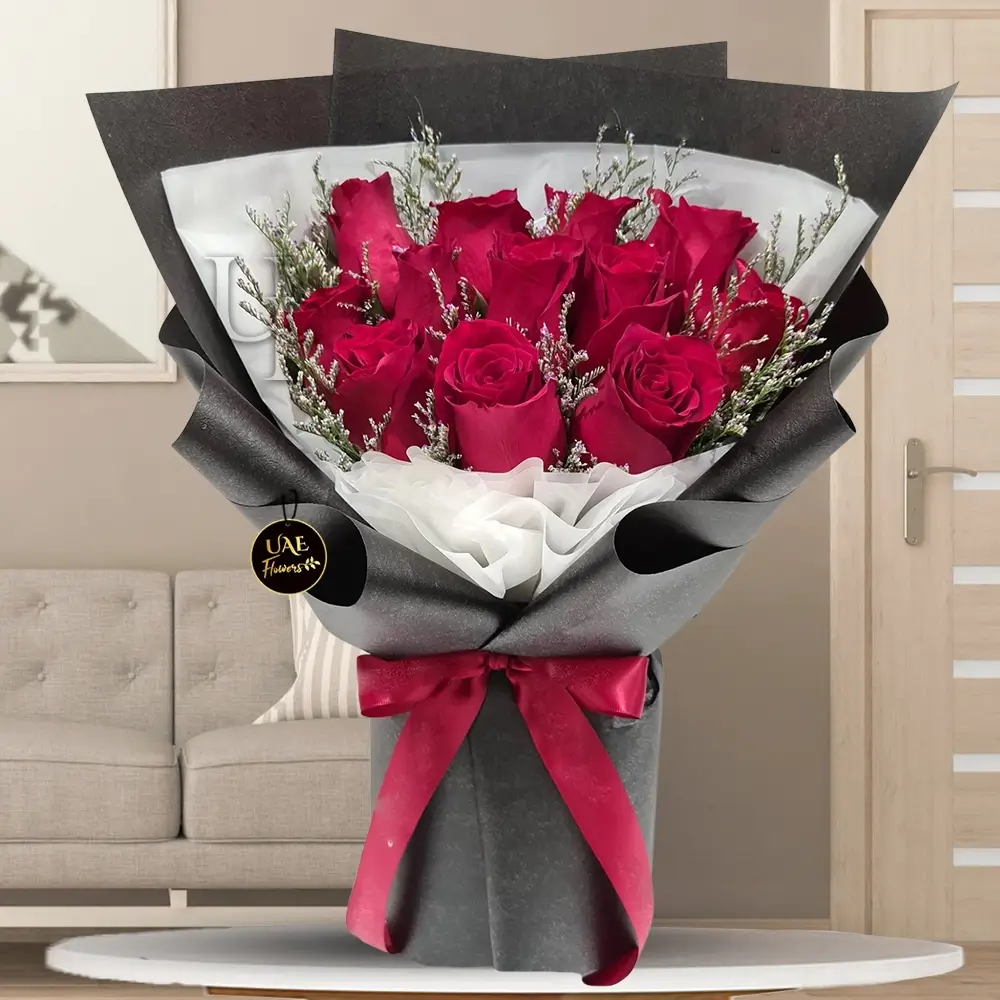 A bouquet of 10 red roses with Limonium fillers in black and white wrapping paper tied with red ribbon