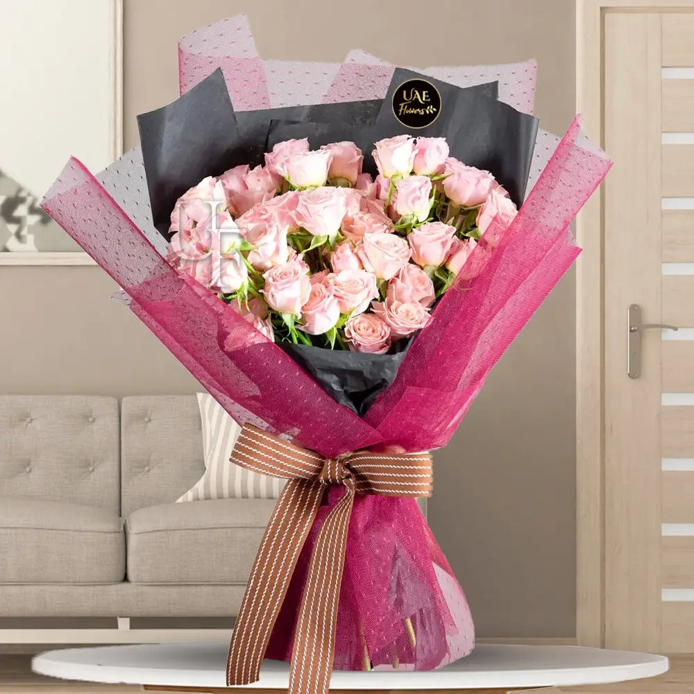 A bouquet of 20 pink spray roses in black wrapping paper and pink net, tied with brown ribbon