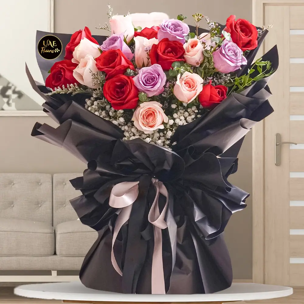 A bouquet of 20 red, peach & purple roses with green fillers, wrapped in black paper and tied with pink & black ribbons