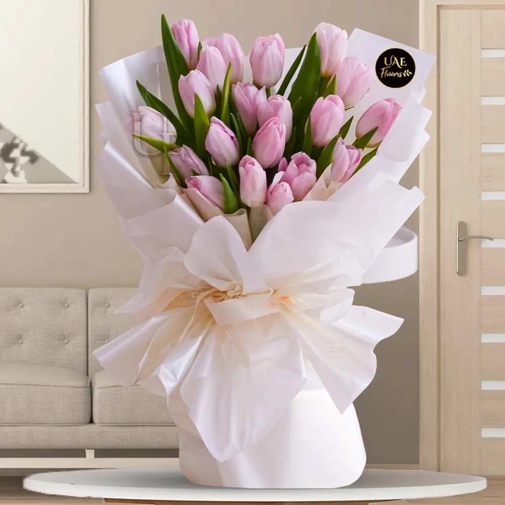 A bouquet of 20 pink tulips with fillers in white wrapped paper tied with white ribbons