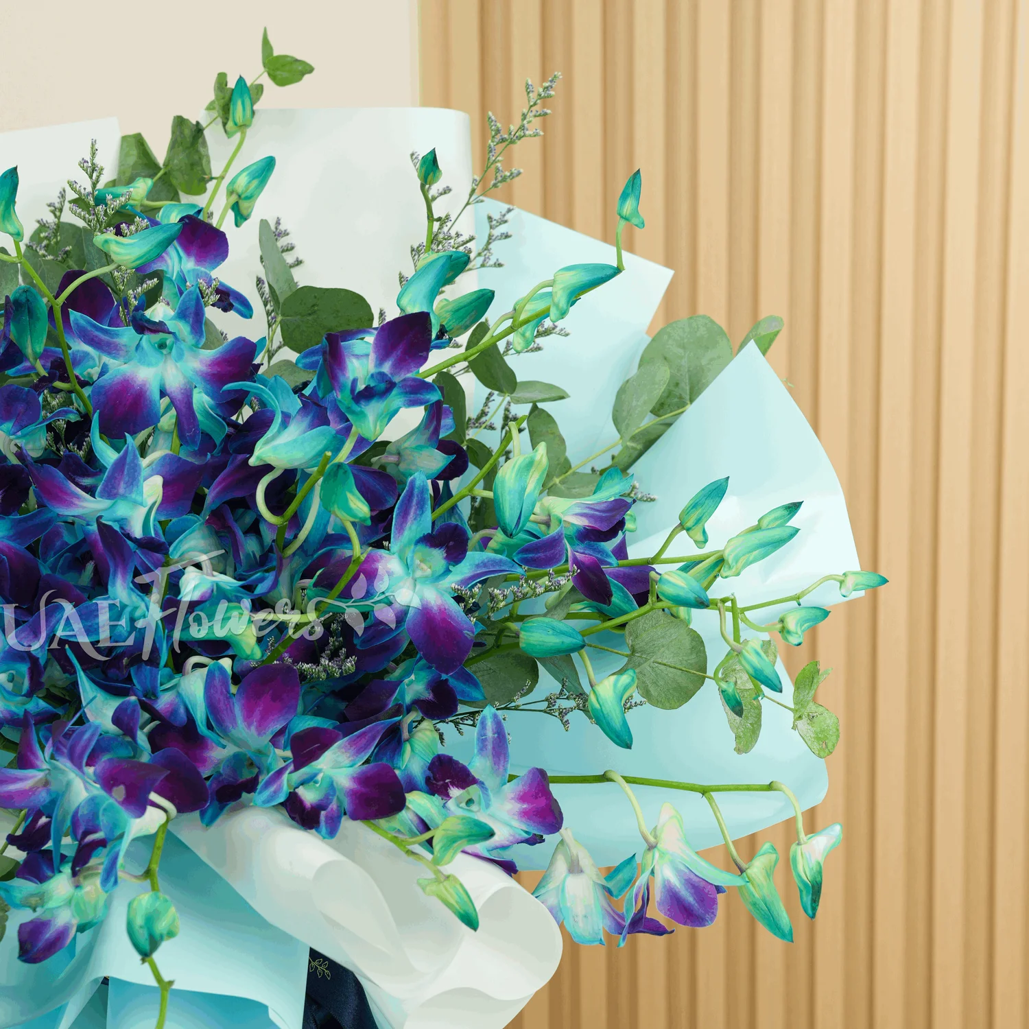 A bouquet of 20 blue orchids with greens and limonium fillers wrapped in blue and white paper tied with blue ribbons
