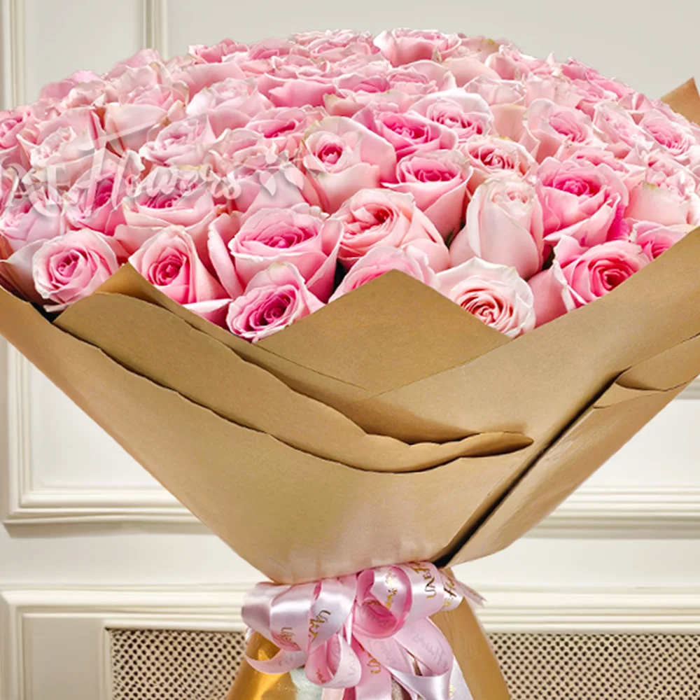 Luxurious bouquet of 100 pink roses, elegantly wrapped in brown paper with a pink satin ribbon. Perfect for anniversaries, birthdays, or heartfelt moments.