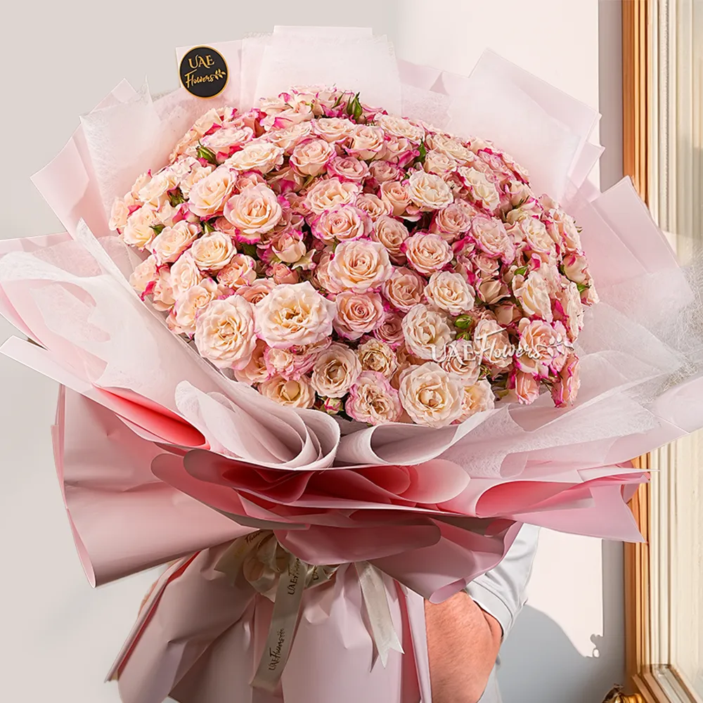 bouquet of 40 pink spray roses in pink wrapping paper tied with ribbon