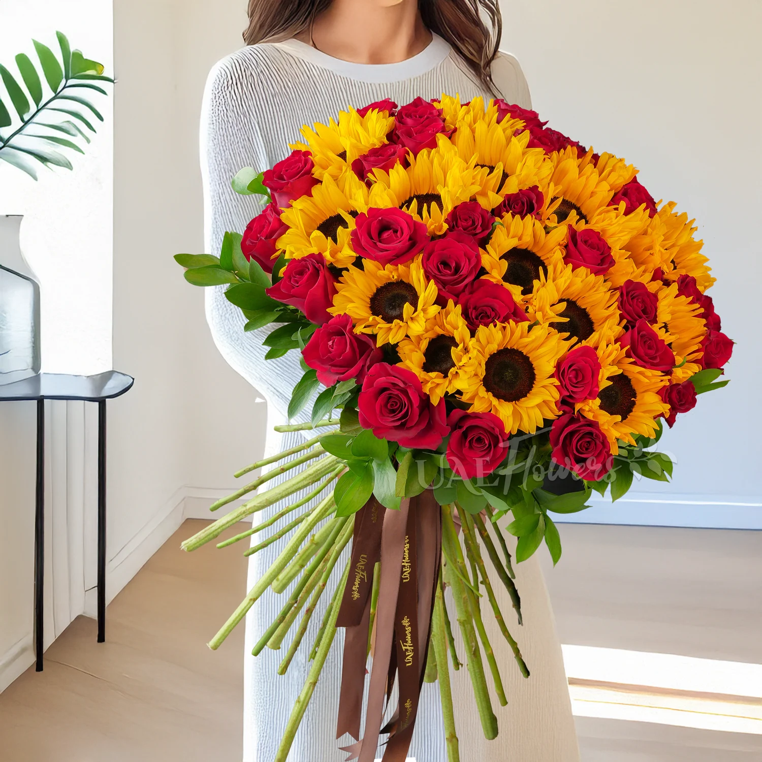 bunch of 20 sunflowers and 25 red roses tied with brown ribbons
